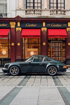 a black car parked in front of a red and gold store on a city street