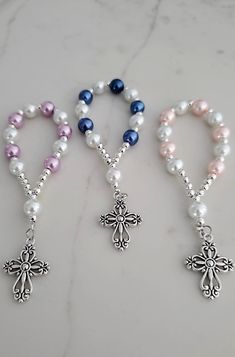 three bracelets with cross charms on them sitting on a marble counter top next to each other