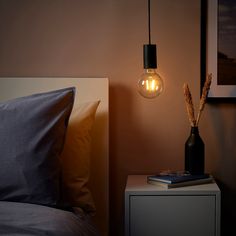 a lamp that is on top of a night stand next to a bed with pillows