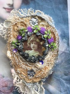 a brooch with an image of a woman on it's face and purple flowers in the center