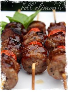 several skewered meats with ketchup and green leaves on the side