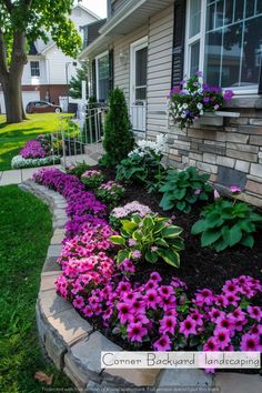 a flower bed in front of a house with purple and pink flowers growing on it