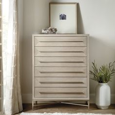 a white vase sitting on top of a wooden dresser