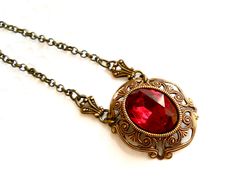 Beautiful victorian style pendant necklace made of a lovely oxidized brass filigree cabochon base, American made, and a vintage ruby red rhinestone cabochon. The size of the cabochon is 13 x 18 mm. The necklength is approximately 49 cm. (19.3 inches) For more jewelry please visit our shop: http://www.minouc.etsy.com For combined shipping please contact us. We also combine shipping with our other Etsy shop where we sell vintage fabrics and finds from Holland and France: http://www.minoucbrocante. Victorian Red Locket Necklace, Red Victorian Locket Necklace, Victorian Antique Gold Necklaces For Valentine's Day, Victorian Antique Gold Necklace For Valentine's Day, Victorian Brass Jewelry For Valentine's Day, Victorian Red Jewelry With Vintage Charm, Antique Red Locket Necklace, Red Ruby Victorian Necklace, Red Oval Victorian Necklace