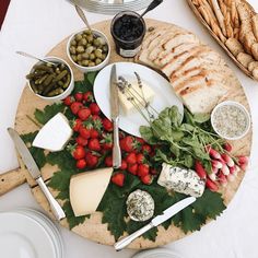 a platter with cheese, strawberries, crackers and olives on it