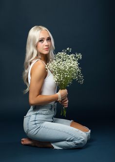 a woman sitting on the floor holding a bouquet of flowers