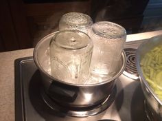 two mason jars sitting on top of a stove next to a pot filled with green beans