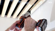 a man is using a drill to fix the wood slats on a ceiling fan