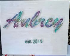 a sign with the word alaska spelled out in beads and sequins on it