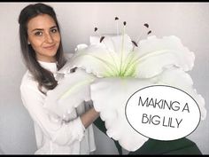 a woman holding a large white flower with the words making a big lily on it