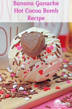 a heart shaped chocolate covered doughnut sitting on top of a wooden cutting board