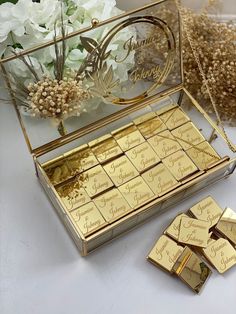 some gold bars are sitting in a box on a table next to white flowers and greenery