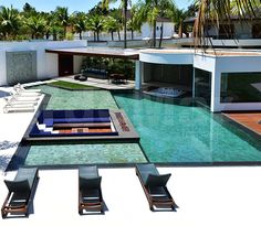 an outdoor swimming pool with lounge chairs around it and palm trees in the back ground