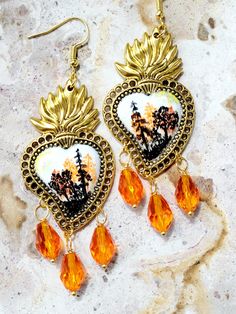 Beautiful hand painted Sacred Heart earrings, with an afternoon landscape, with pines and trees painted in black and orange tones, adorned with orange glass beads, these earrings are a pair of small paintings made in miniature in each of the earrings, they have differences because they are painted individually, 100% hand painted work, you will be surprised by the unique beauty. These beautiful artisanal and artistic earrings are unique pieces, they are hand painted which makes them very special, they are the ideal gift to make a person feel special, you can combine them with any type of clothing from jeans to an evening dress, you will surely attract attention on any holiday or work day that you wear them. *Remember to add our store to favorites ♥ to receive updates on all our news! *The A Artistic Earrings, Mexican Earrings, Multicolor Earrings, Orange Tones, Make A Person, Black And Orange, Unique Beauty, Small Paintings, Feel Special