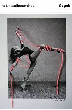 a woman in black leotard holding a red rope with both hands and feet