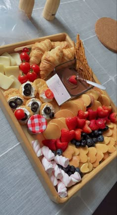 an assortment of cheeses, fruit and crackers in a tray on a table