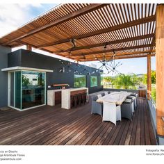 an outdoor kitchen and dining area on a deck with wooden flooring, covered by a pergolated roof