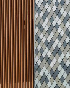 the side of a building with wooden slats on it and a clock in front