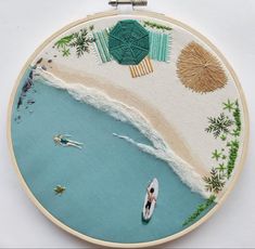 an embroidery project with people in boats on the water and palm trees around it,