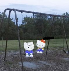 two hello kitty dolls sitting on a swing set