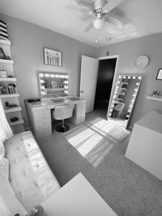 a black and white photo of a bedroom with lights on the ceiling, vanity mirror, desk and bed