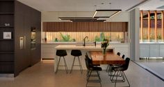 an image of a modern kitchen setting with bar stools in the foreground and wood paneling on the back wall