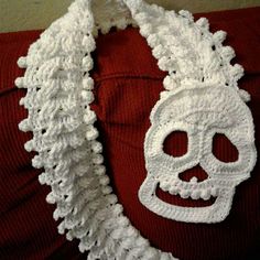 a white crocheted skull on a red sweater