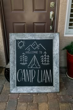 a welcome to camp lamm sign in front of a door with potted plants