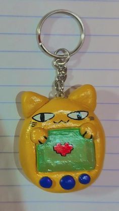 a yellow cat shaped keychain with a green screen on it's face