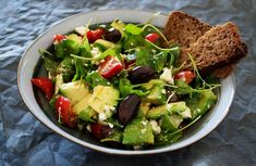 a salad in a bowl with bread on the side