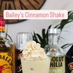 bailey's cinnamon shake with whipped cream in a glass next to bottles of booze