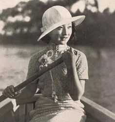 an old black and white photo of a woman in a boat holding a baseball bat