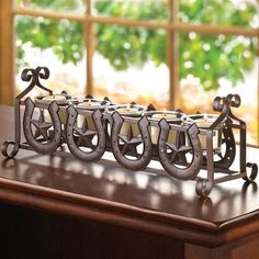 a metal candle holder sitting on top of a wooden table next to a large window