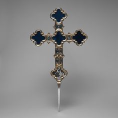 a blue and gold cross with a knife sticking out of it's center piece