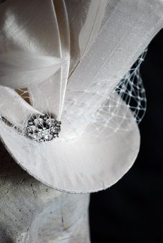 This simple and elegant bridal mini top hat is covered with beautiful ivory silk shantung. It is embellished with ivory veil, a luxurious spray of curled ostrich plums and a sparkling flower shaped rhinestone button. Also available in white and black here : https://www.etsy.com/shop/BizarreNoir?ref=seller-platform-mcnav&section_id=14329940 If you're interested in another color, please, send me a message to talk about your options. This mini top hat is fully lined with satin and attaches to t Vintage Wedding Hat With Pinched Crown, Vintage Wedding Costume Hat With Pinched Crown, Silver Curved Brim Hat For Wedding, Fitted Round Crown Wedding Hat, Fitted Costume Hat With Round Crown For Wedding, Vintage Cream Costume Hat For Wedding, Fitted Cream Cloche Hat For Wedding, Elegant Cream Mini Hat For Ceremonies, Gatsby Style Wedding Fascinator With Short Brim