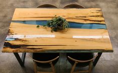 a wooden table with two chairs and a potted plant on the top in front of it