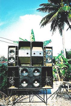 there are speakers stacked on top of each other in front of a palm tree and blue sky