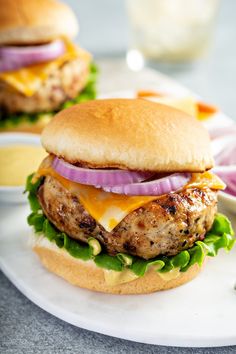 a chicken burger with cheese, onions and lettuce sitting on a counter top