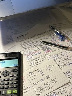 a calculator sitting on top of a table covered in papers