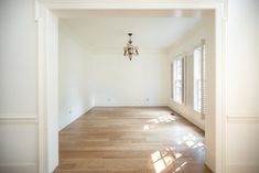 an empty room with hard wood floors and chandelier hanging from the ceiling,