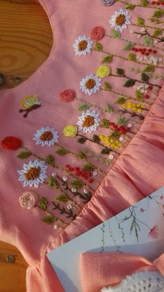 a pink dress with flowers on it next to a piece of paper and some scissors