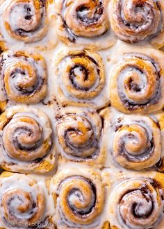 cinnamon rolls with icing sitting on top of each other in a casserole dish