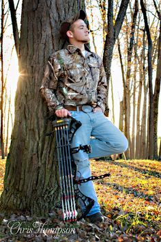 a man leaning against a tree with his bow