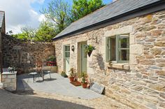 an old stone house with potted plants on the outside and patio area in front