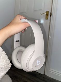 a person is holding up their headphones in front of the door with her hand