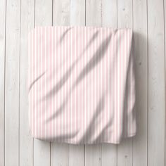 a pink and white striped bed spread on top of a wooden floor next to a wall