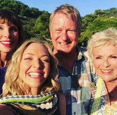 three women and one man are smiling for the camera