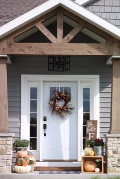 a front porch decorated for fall with pumpkins and gourds