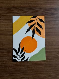 a piece of paper with an orange and black design on it sitting on top of a wooden table