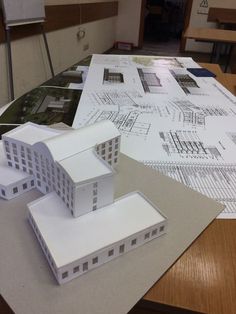 a model of a building sitting on top of a table next to some blueprints